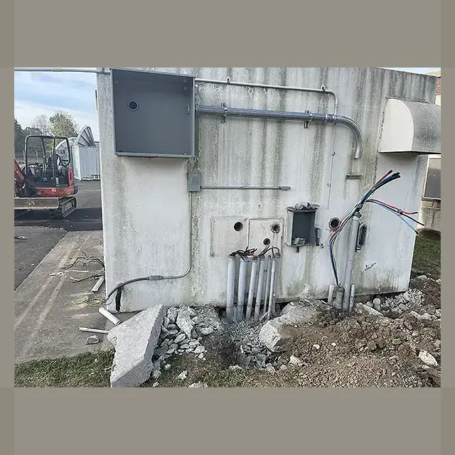 We started with a site visit and provided the client with a free quote. Once approved, we secured all required permits. Then our team starts disconnecting all utilities and prepare the structure for demolition. Side of a mobile home with exposed wires and broken concrete during utility disconnection by Next Day Demolition.