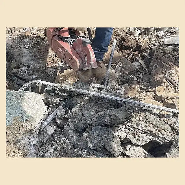 Next Day Demolition worker cutting steel rebar from broken concrete during cleanup.